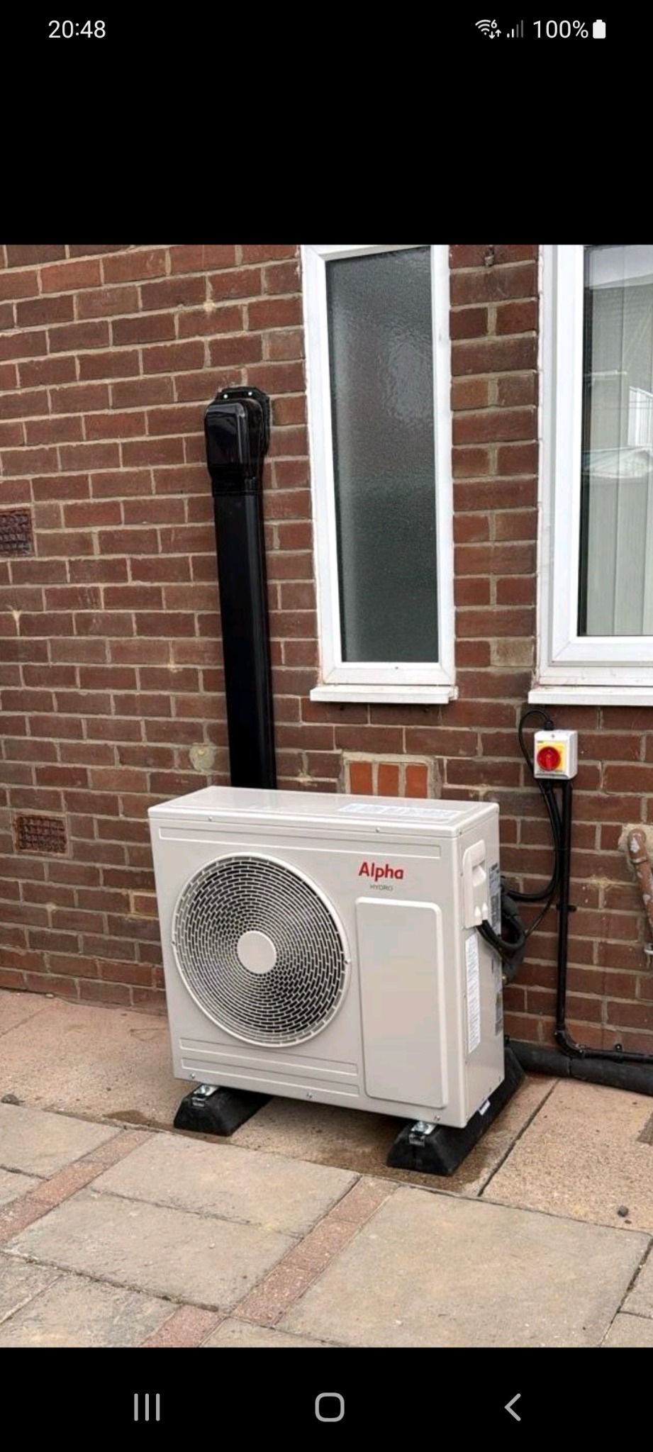 Air source heat pump fitted outside a brick house